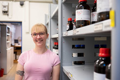 Junge Frau im Lager. Es stehen Flaschen im Schrank.